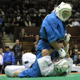 Combate en el suelo durante una competencia de Kudo: control de espalda con casco protector